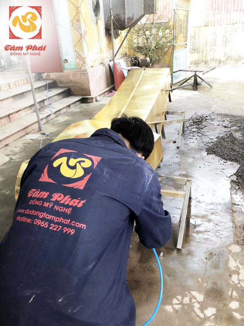 Nghệ nhân của đồ đồng Tâm Phát đang tiến hành mạ vàng một cạnh của công trình Tượng Đài
